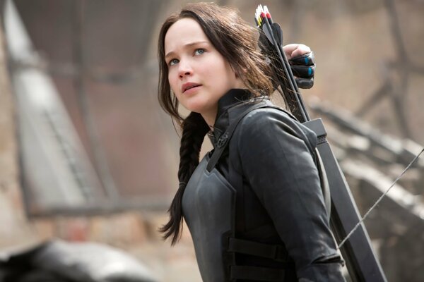 A character from the Hunger Games stands with a bow on the edge