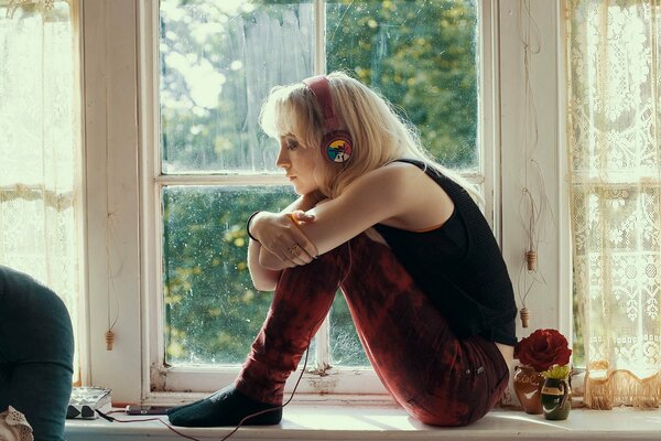 A girl on the windowsill listens to music