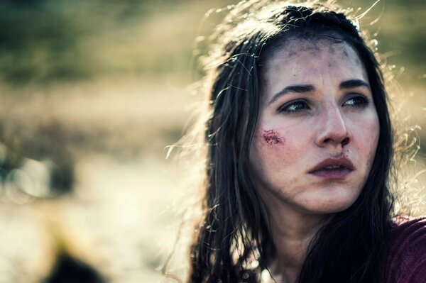 Portrait of a girl with injuries on her face, looking into the distance