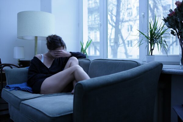 Fille assise sur le canapé avec le visage fermé