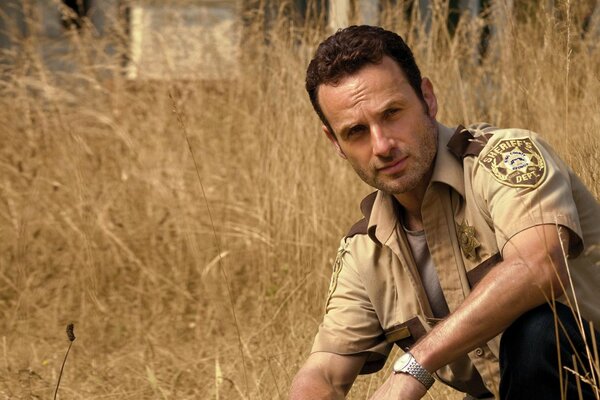 A man in a police uniform among the dry grass