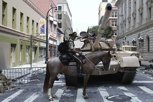 Ein Polizist auf einem Pferd steht vor einem Panzer