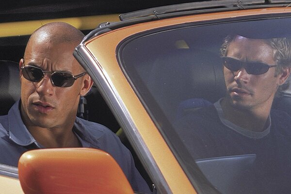 Dwóch mężczyzn w pomarańczowym samochodzie