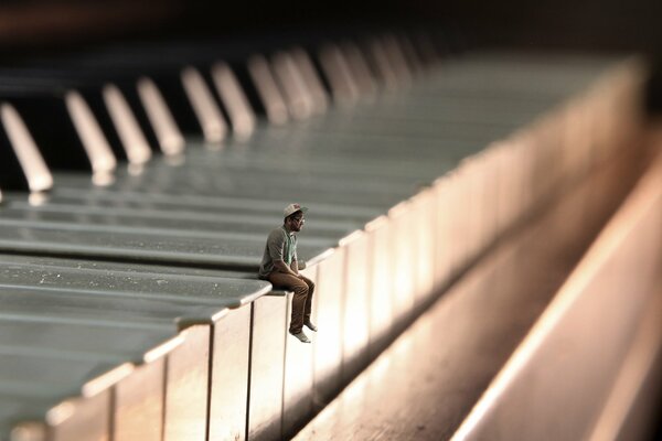 Petit homme assis sur le piano