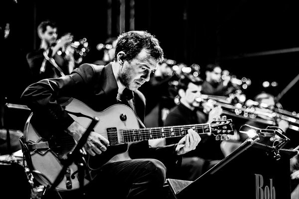 Das Foto des Orchesters mit dem Gitarristen im Vordergrund