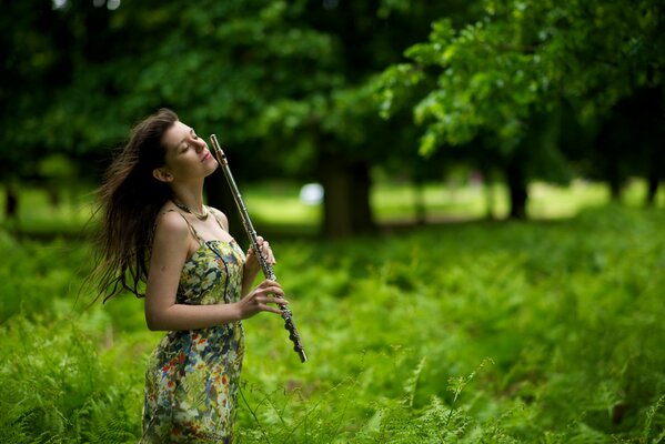 Mädchen spielt Flöte im Wald