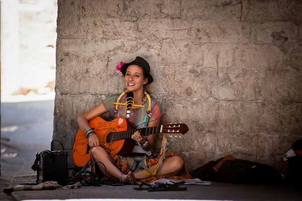 A girl with a guitar against the wall