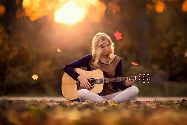 Bella ragazza con chitarra su sfondo fogliame