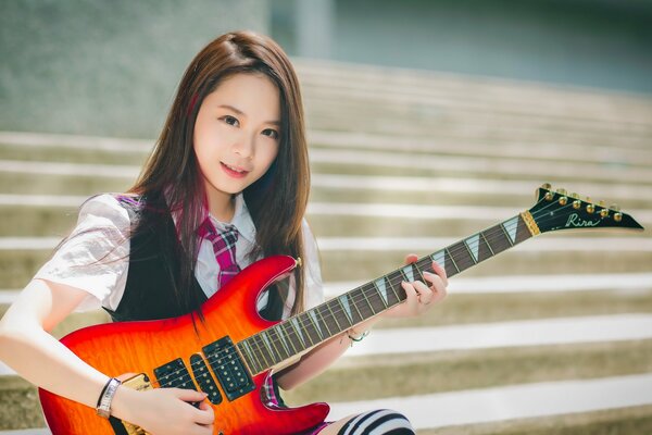 Bella ragazza asiatica con la chitarra