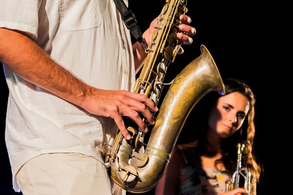 A girl musician looks out from behind a saxophone