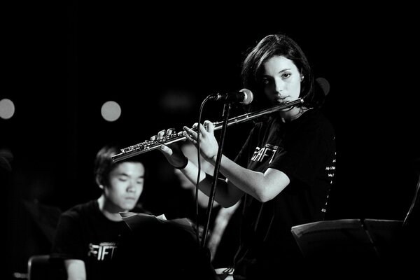 The girl plays the flute. Musician in the background