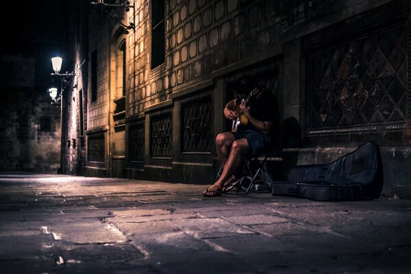 Un hombre con una guitarra en la calle por la noche