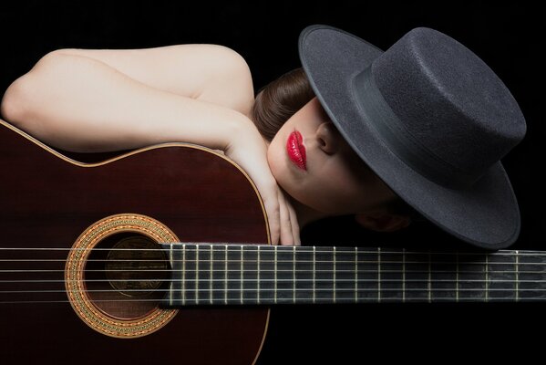 A girl in a hat with red lipstick and a guitar