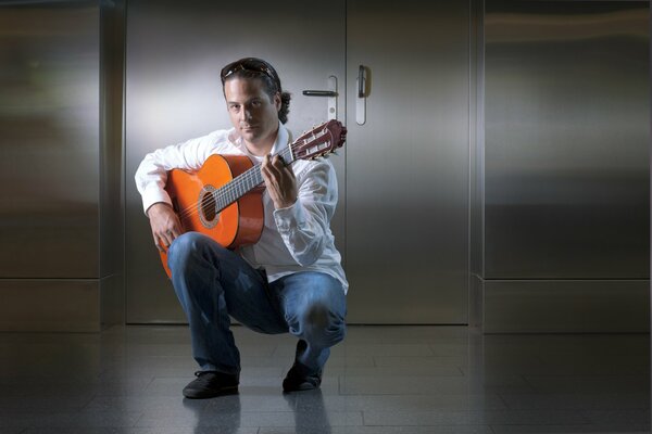 Gitarzysta David w białej koszuli i niebieskich spodniach trzyma gitarę