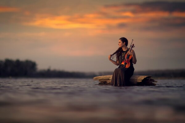 A girl with a violin in the middle of the water