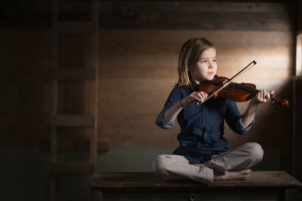 A girl sitting playing the violin