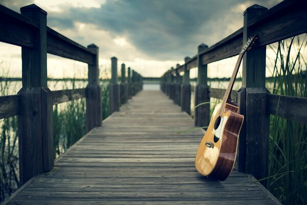 Gitarre am Pier unter bewölktem Himmel