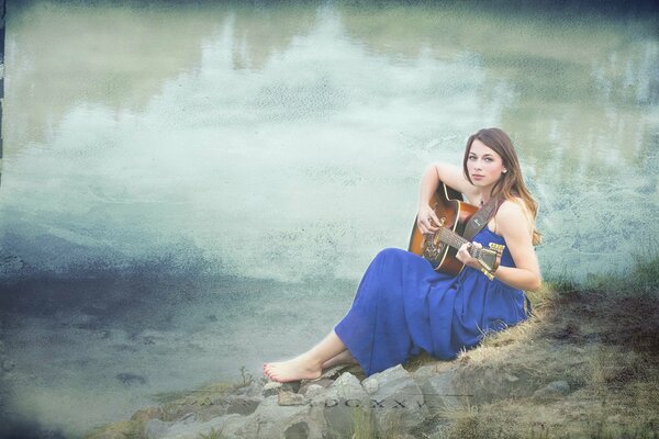 A girl with a guitar on the riverbank