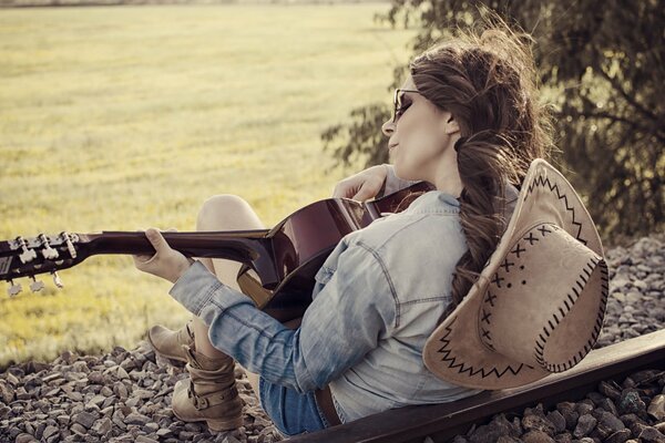 Fille avec un chapeau joue de la guitare