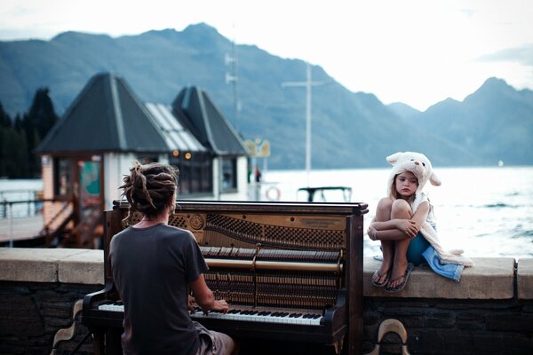 Sonnenuntergang in Neuseeland. Ein Klavier und ein Mädchen in einer Mütze