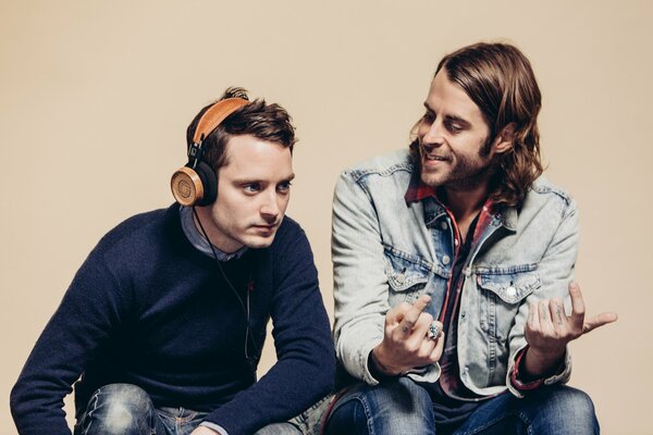 Elijah Wood and Zach Cowie are talking. The man with the headphones