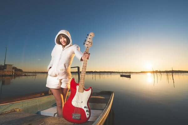 Mädchen mit roter Gitarre auf Sonnenuntergang Hintergrund