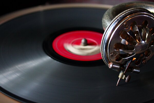 A gramophone needle is placed over a vinyl record with a red label