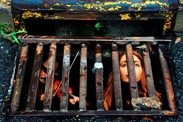 Musicians sit behind a sewage grate