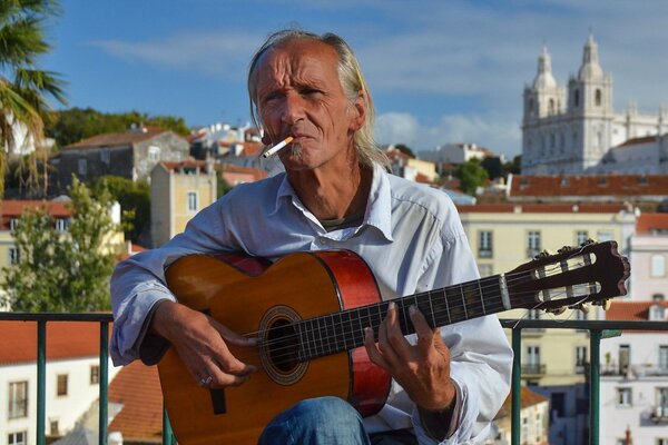 Ein Mann im Alter mit einer Zigarette spielt Gitarre