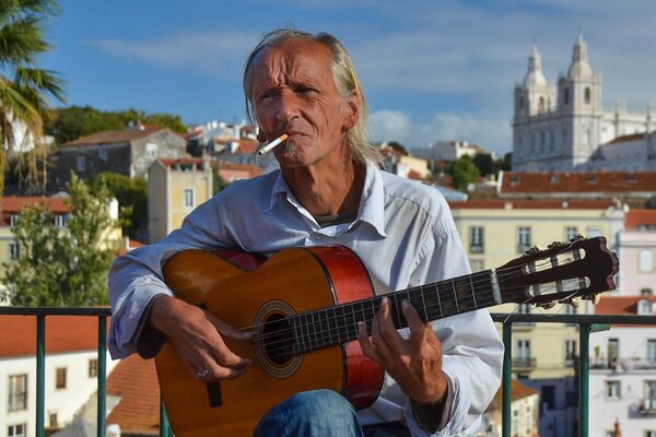 Un homme âgé avec une cigarette joue de la guitare