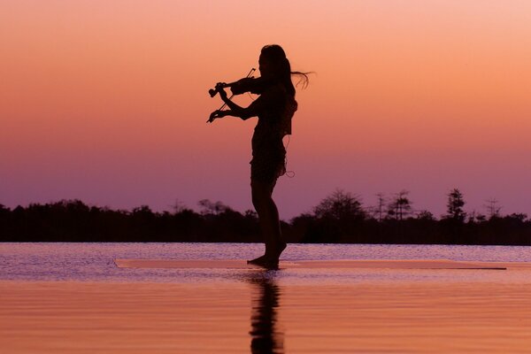 Chica tocando el violín por la noche