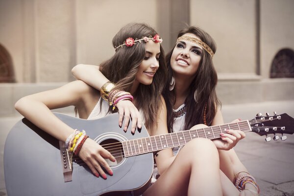 Dos chicas hippies tocando la guitarra