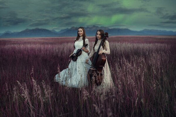 Dwie dziewczyny w polu grają na skrzypcach