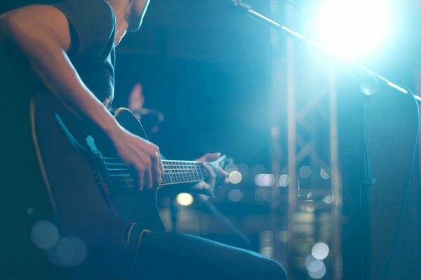 The musician plays a six-string guitar