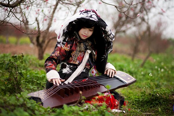 Девушка с музыкальным инструментом в саду