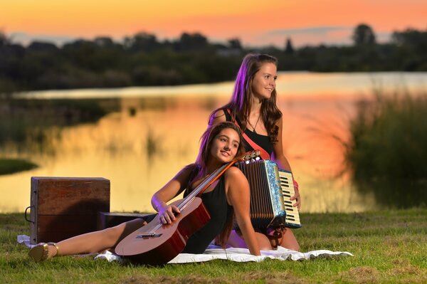 Dos chicas se sientan en un claro con una guitarra y un baian