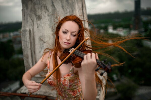 A red-haired girl plays wind music on a violin