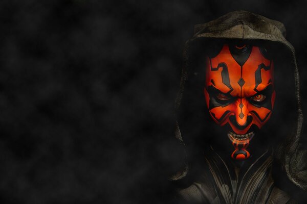 A man in a scary, red mask on a dark background
