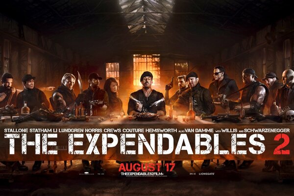 The team of the expendables are sitting at the table, a poster for the movie