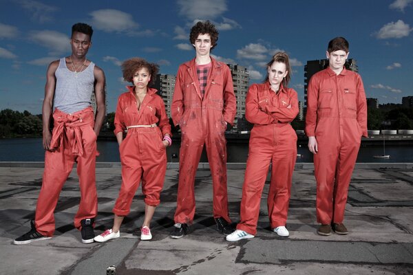 Actores de la serie Escoria con trajes rojos