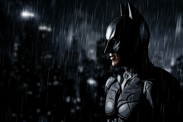 Batman se tient dans le noir sous la pluie