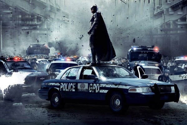 Batman de pie en un coche de policía