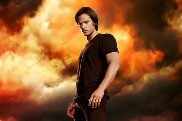 Sam Winchester from Supernatural stands against the red sky