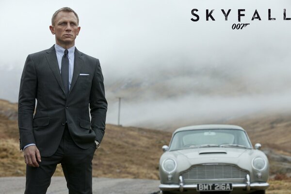 Агент 007 стоит у машины в черном костюме