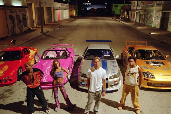 Four people against the background of four cars