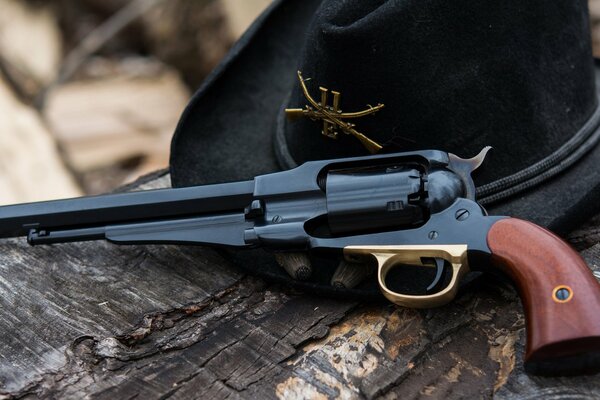 Revolver 1858 e cappello su un tronco d albero secco