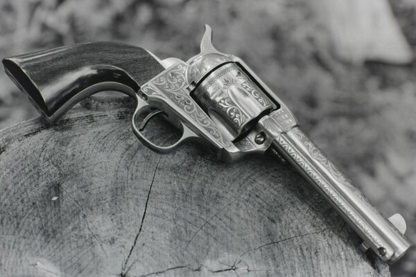 Старинный револьвер с узорами лежащий на пне