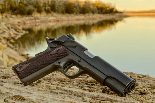 Self-loading pistol on the background of the shore and lake