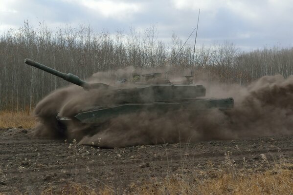 A battle tank is moving along the road at high speed