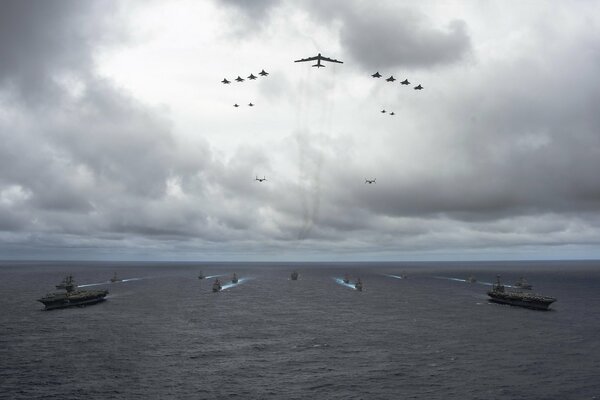 A flock of planes flies over warships